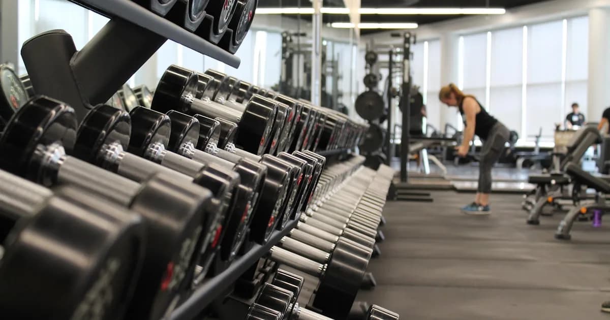 Dumbbell rack on a gym floor with members training in the background