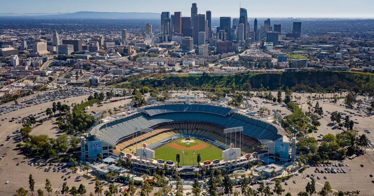 Aerial view of a baseball stadium with a city skyline behind it
